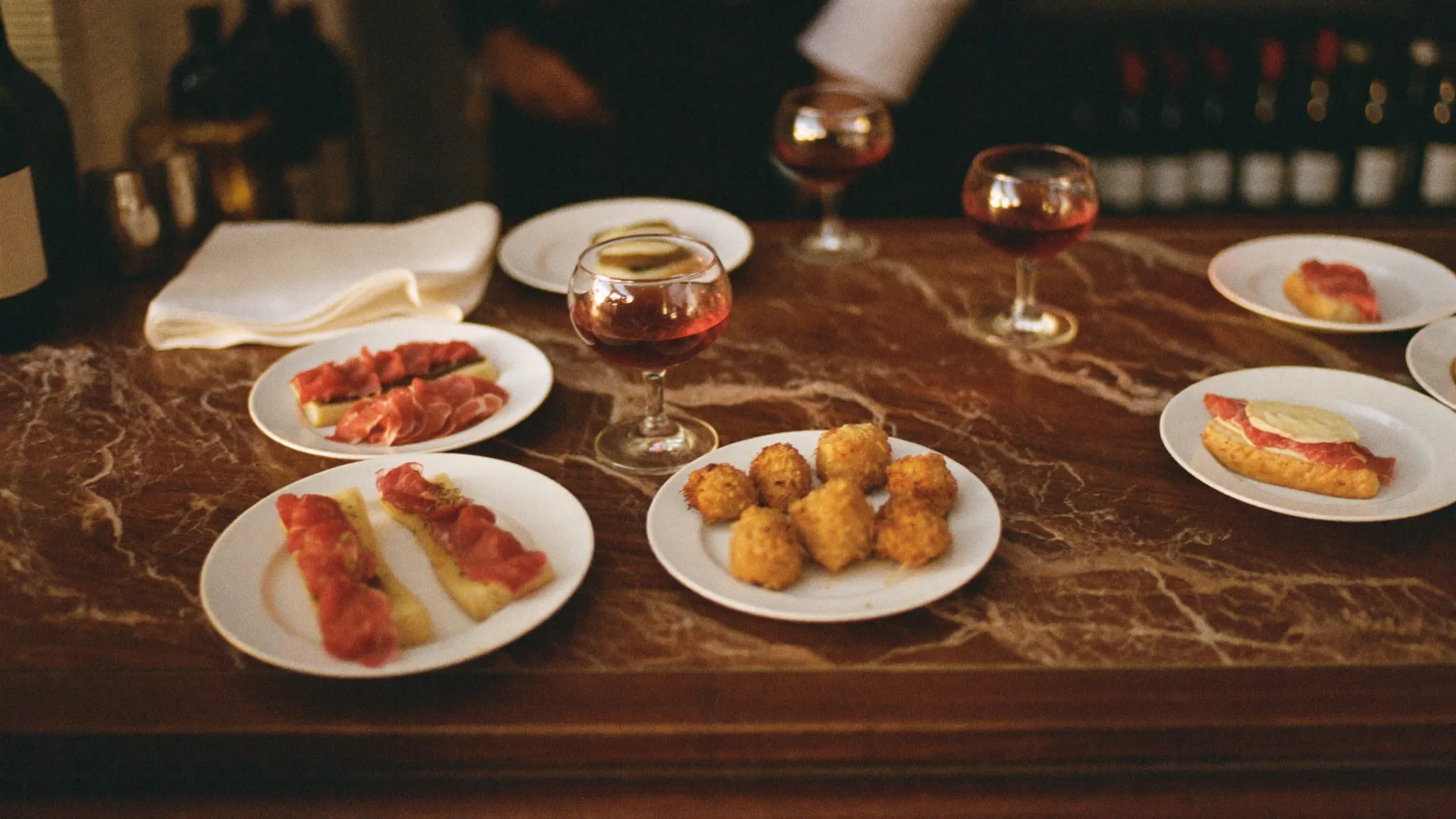 Il bancone di Ombra con cicchetti e bicchieri di vino rosso nella luce calda della sera