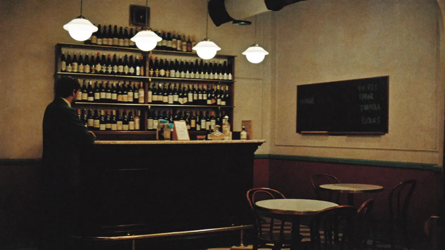 L'interno di un bacaro milanese: bancone, bottiglie, lampade calde e lavagna